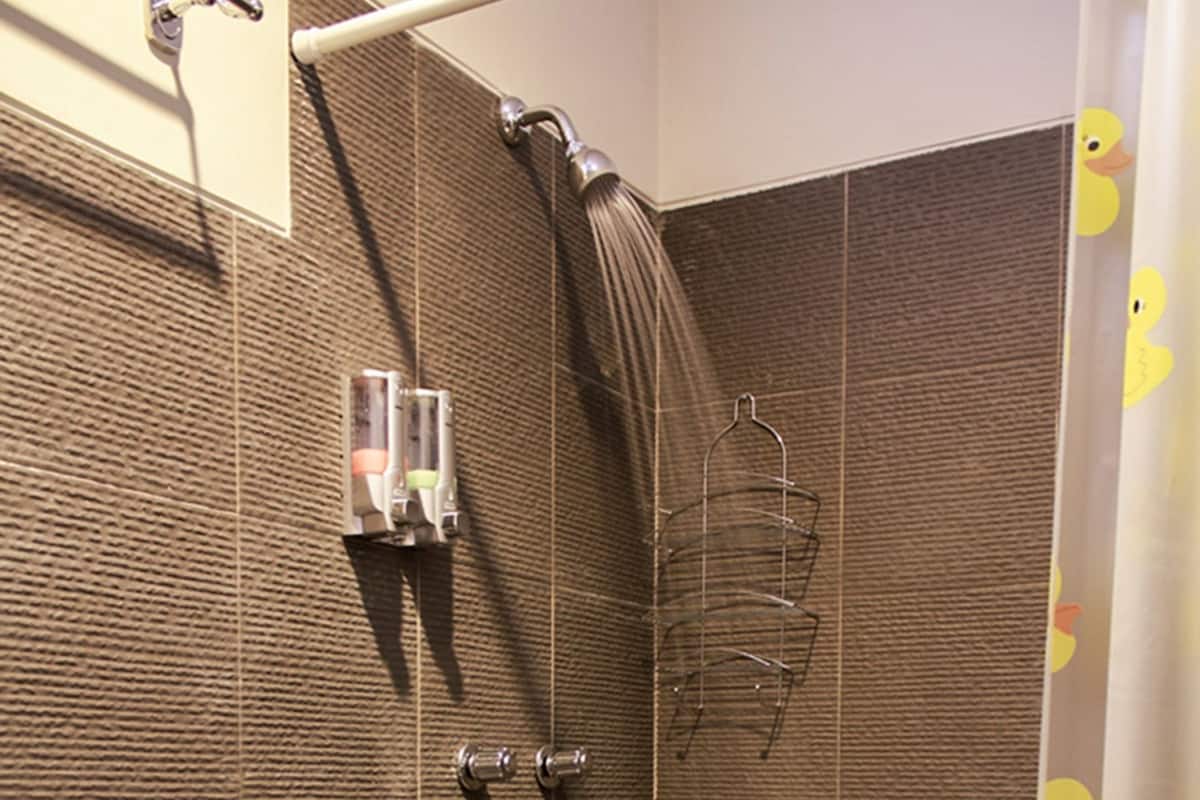 A bathroom with a toilet, a shower, and a tiled floor.