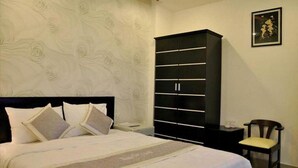 A bedroom with a bed, a wardrobe, and a chair. - Manh Cuong Hotel (Da Nang)