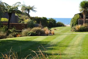 A well-maintained lawn with a wooden deck and a view of the ocean. - Adrift In Golden Bay (Parapara)