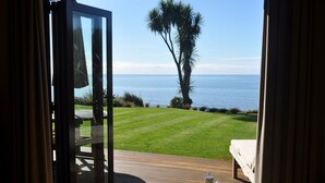 A room with a view of the ocean, a wooden deck, and a breakfast tray on the floor. - Adrift In Golden Bay (Parapara)