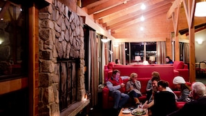A cozy interior with stone walls, wooden beams, and red seating.
