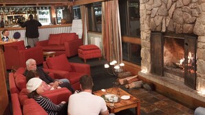 A cozy lounge area with red sofas and a stone fireplace.