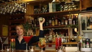 A bar area with shelves stocked with bottles and glasses.