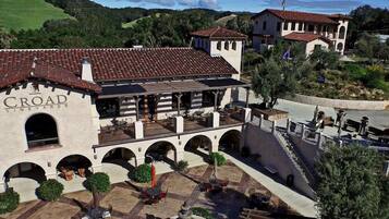 A vineyard estate with a courtyard featuring outdoor seating, a fountain, and a view of the surrounding landscape.