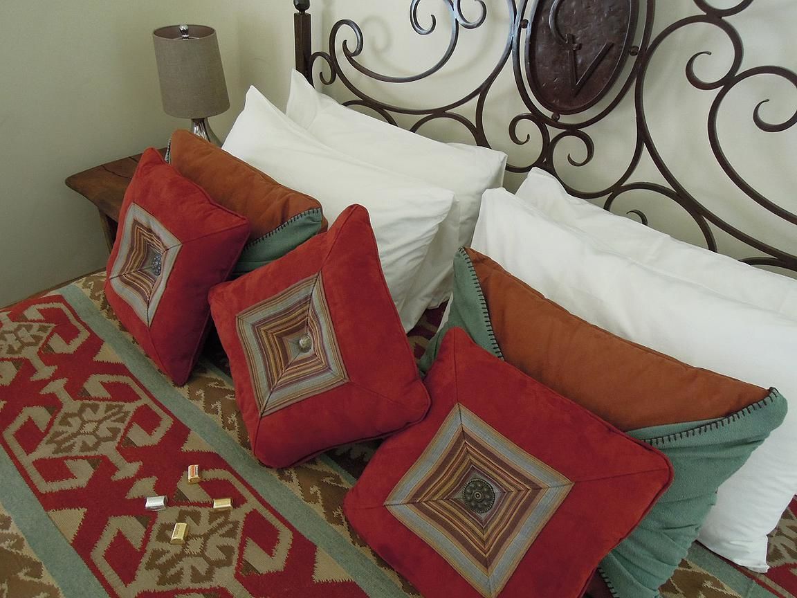 A bed with multiple pillows and a patterned rug.