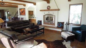 A living room with a fireplace, leather sofa, and a cowhide rug.