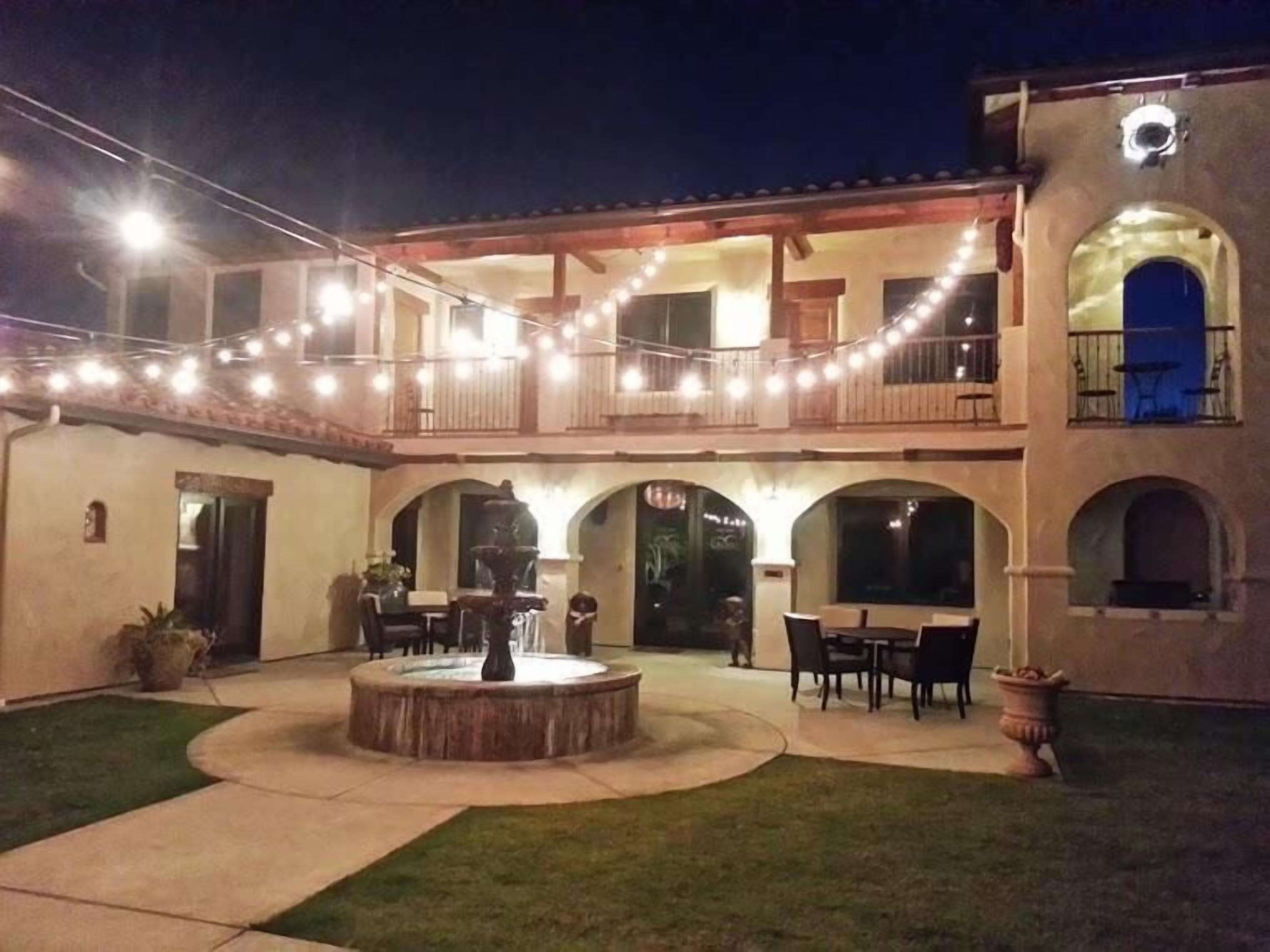 A two-story building with a courtyard, outdoor seating, and string lights.