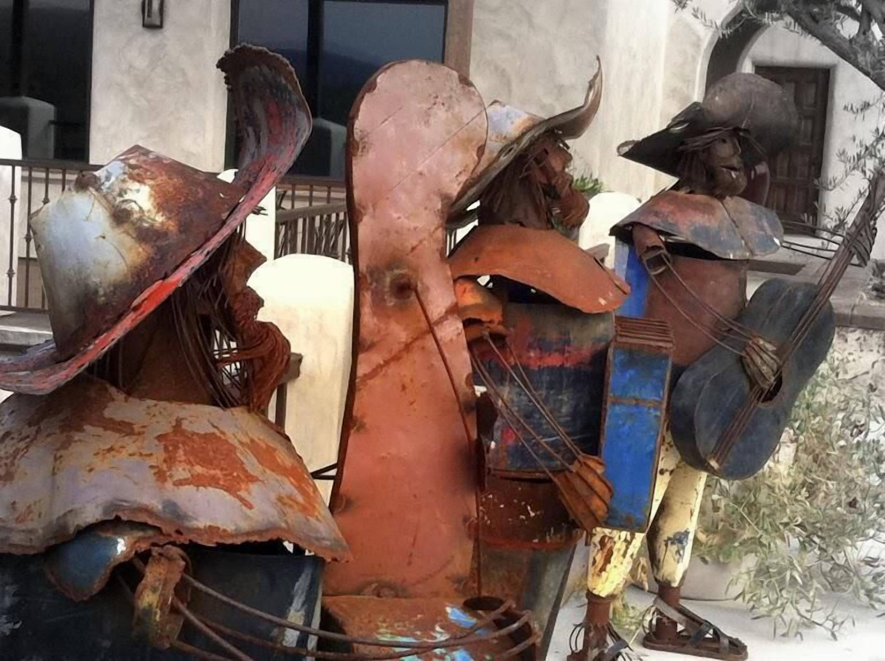 Una escultura de un toro con jinete, hecha de metal oxidado, en un entorno exterior.