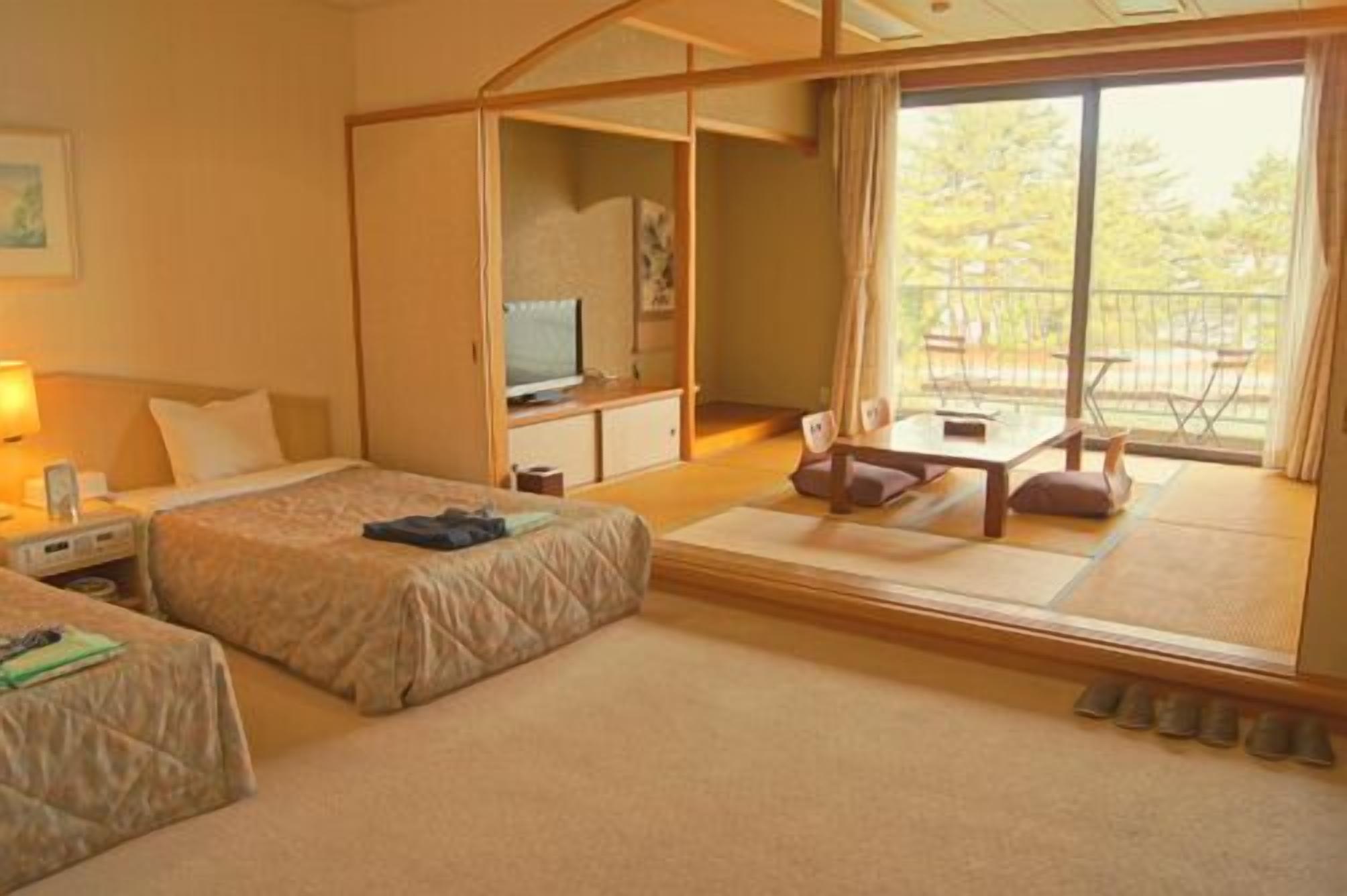 Une chambre d’hôtel avec deux lits, une télévision, une petite table et un balcon avec vue.
