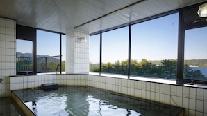 A hot tub with tiled walls and large windows offering a view of a mountainous landscape. - Amano Hashidate So (Miyazu)