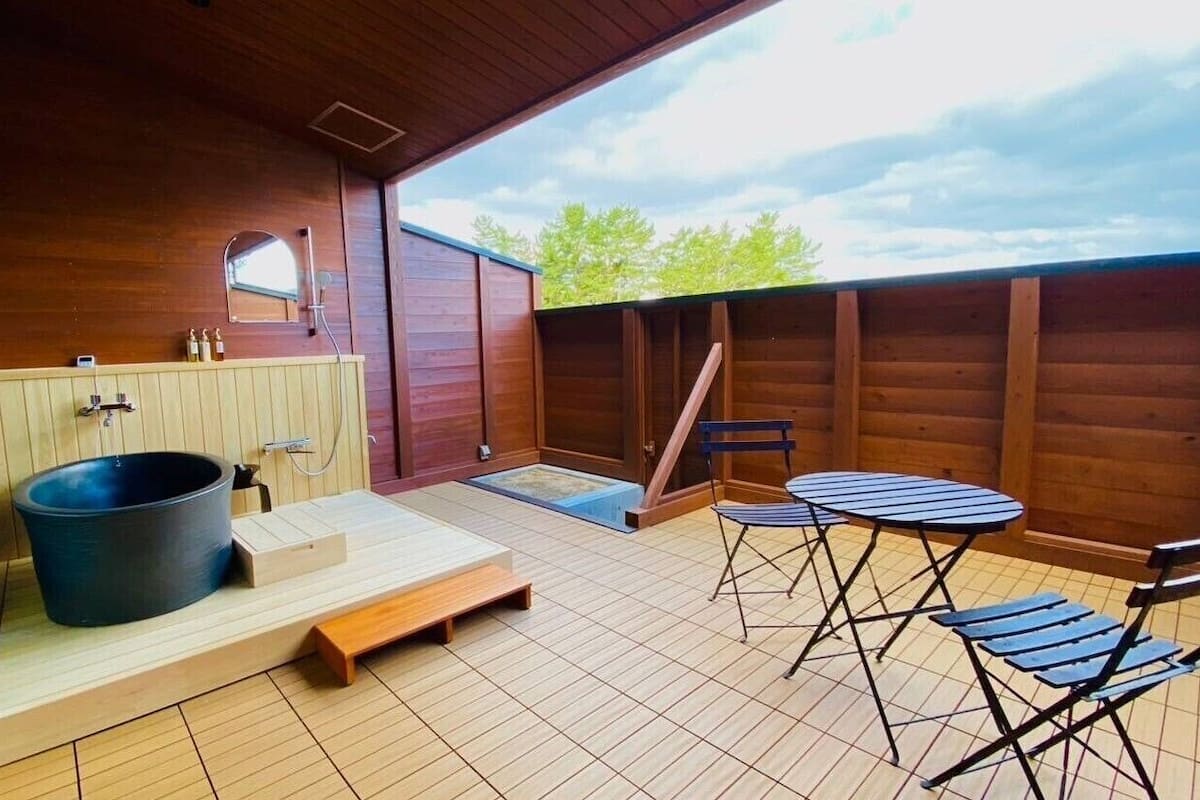 A wooden deck with a hot tub, a small table, and chairs.