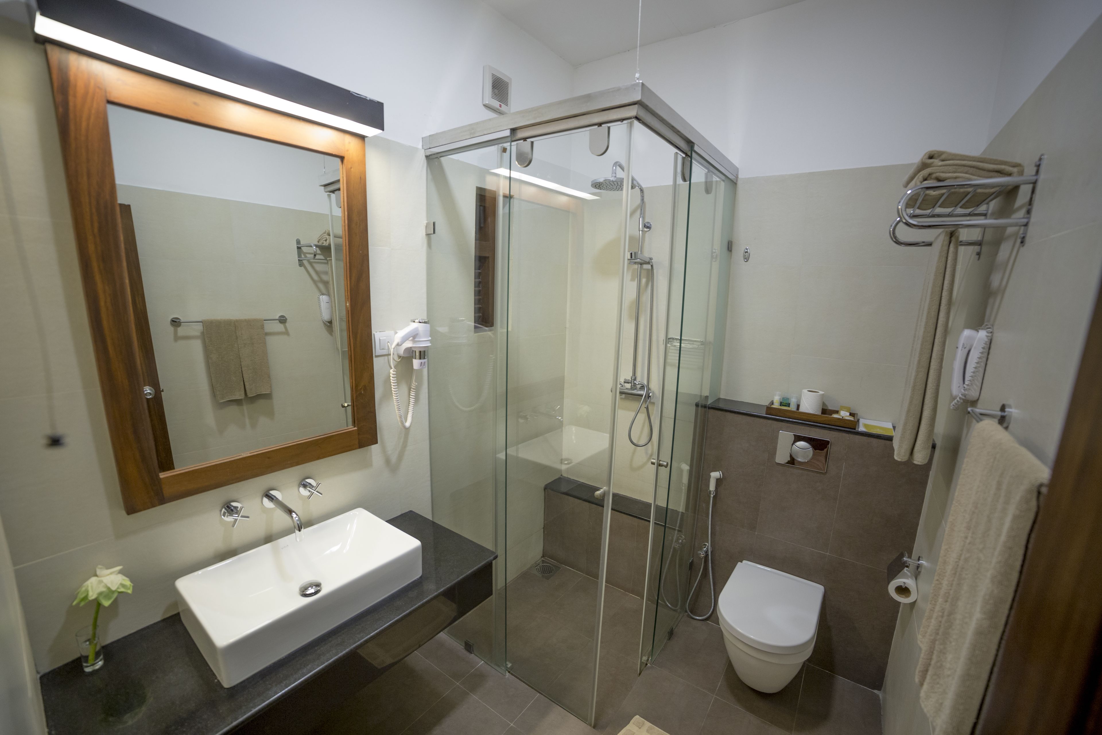 Un bany modern amb dutxa de vidre, un lavabo blanc i un vàter.