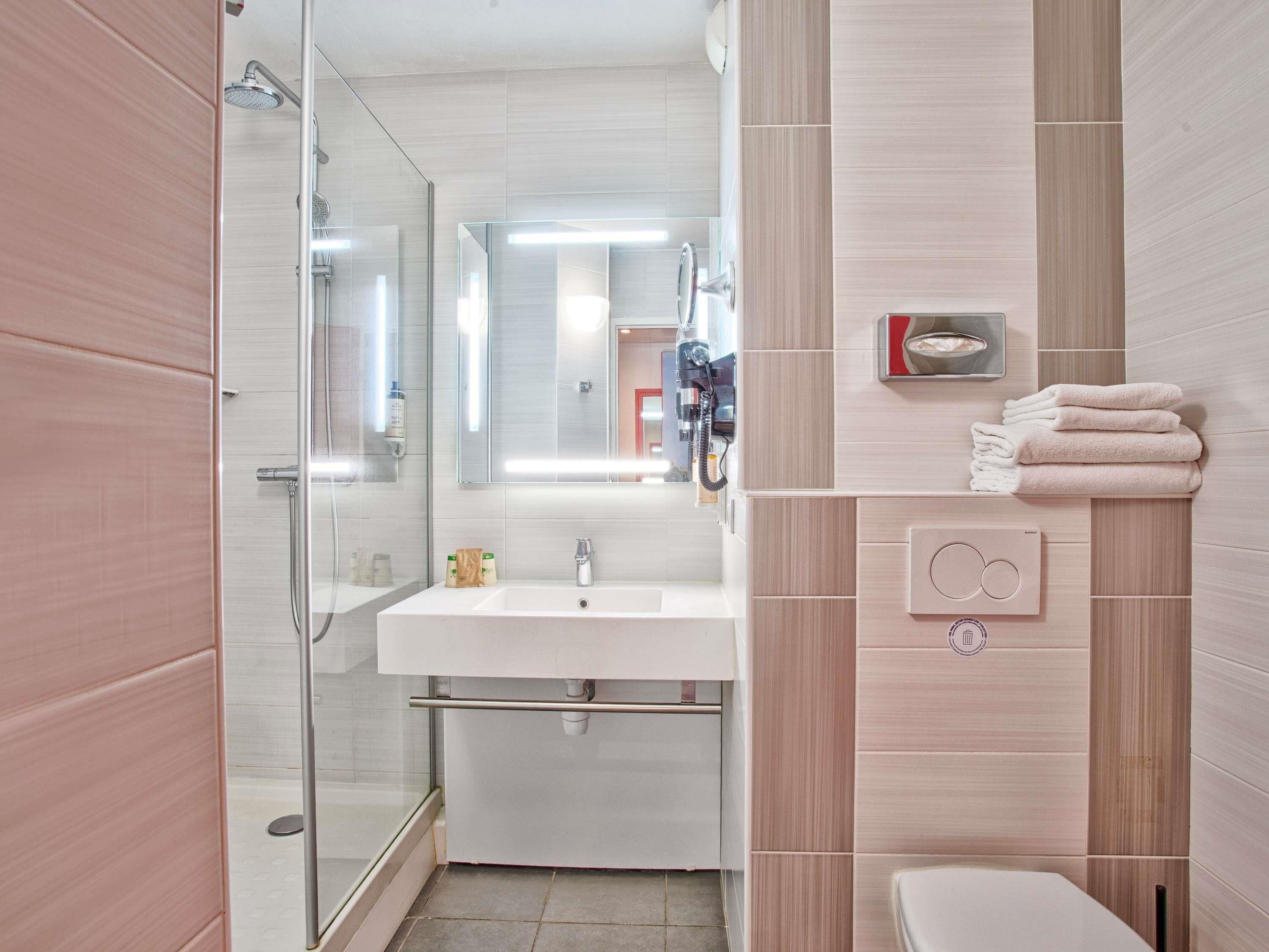 A modern bathroom with a glass shower enclosure, a white sink, and a toilet.