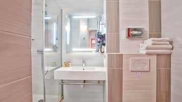 A modern bathroom with a glass shower enclosure, a white sink, and a toilet.