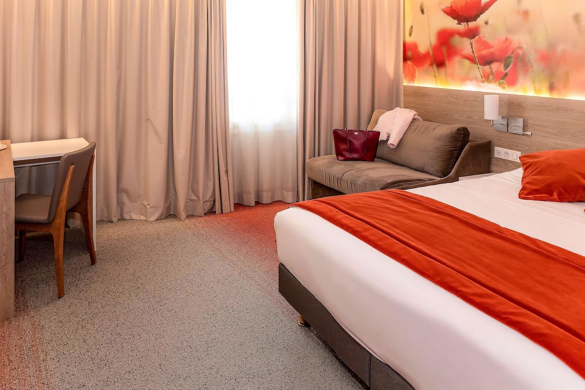 Ett hotellrum med en säng, ett skrivbord och en stol.