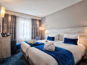 Een hotelkamer met twee bedden, een bureau en een stoel.