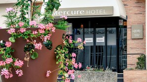 A Mercure Hotel entrance with a large planter of pink flowers in front. - Mercure Trouville-sur-mer (Trouville-sur-Mer)