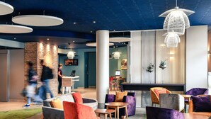 A modern lounge area with a reception desk, seating arrangements, and a decorative chandelier. - Mercure Trouville-sur-mer (Trouville-sur-Mer)