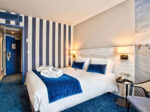 Ein Hotelzimmer mit Bett, Schreibtisch, Stuhl und Blick auf den Strand.