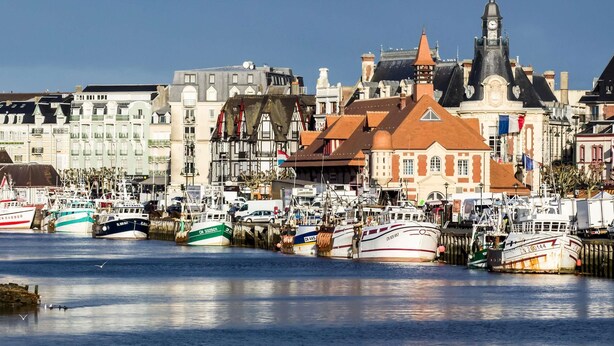 A harbor with boats docked, a prominent building with a clock tower, and a variety of other structures. - Mercure Trouville-sur-mer (Trouville-sur-Mer)