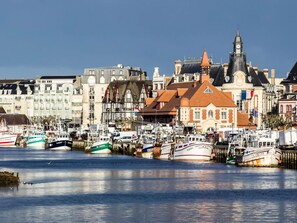 A harbor with boats docked, a prominent building with a clock tower, and a variety of other structures. - Mercure Trouville-sur-mer (Trouville-sur-Mer)