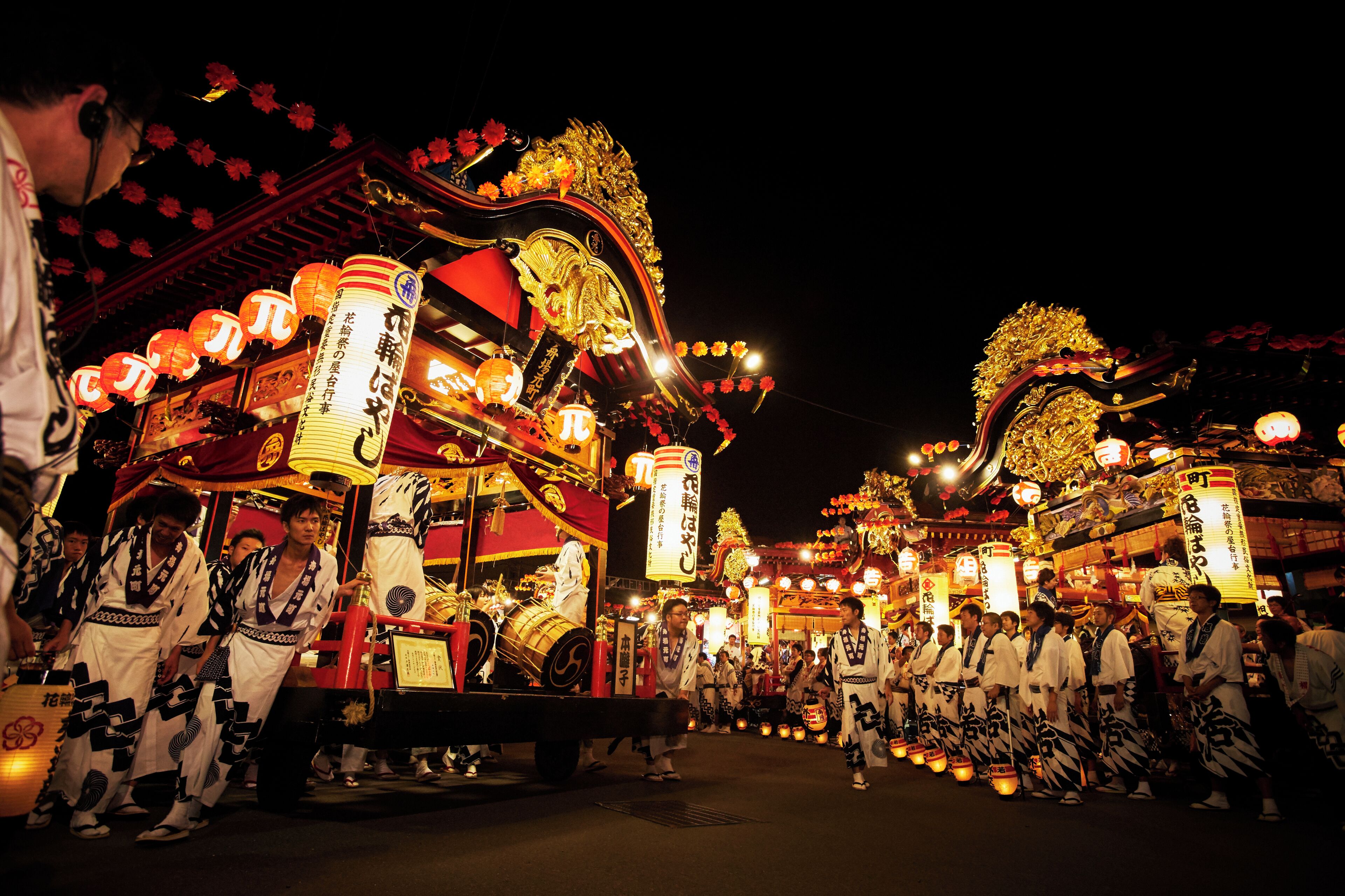 Un festival japonés tradicional con carrozas ornamentadas y participantes con vestimenta típica.