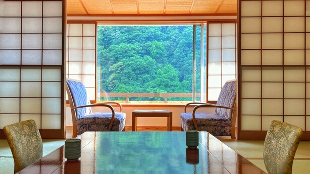 Una habitación tradicional japonesa con suelo de tatami, una mesa baja y dos sillas con estampado.