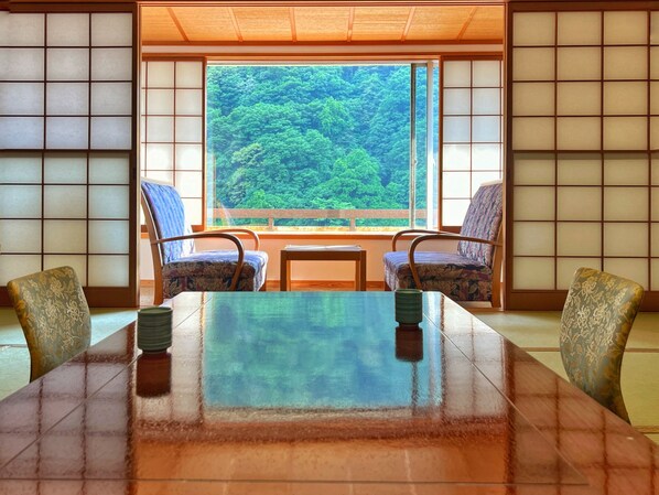 A traditional Japanese-style room with tatami flooring, a low table, and two patterned chairs. - KAMENOI HOTEL AKITA YUZE (Kazuno)