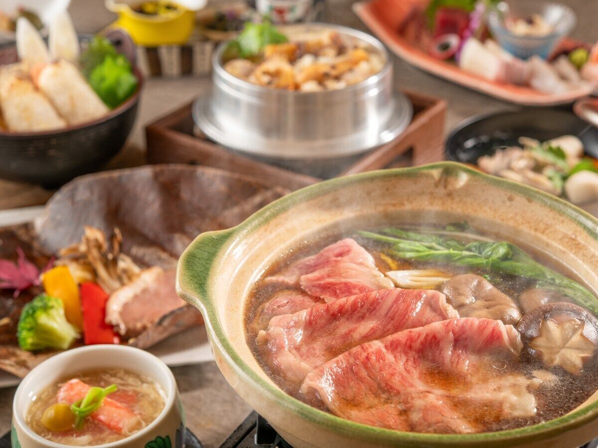 A variety of dishes including a bowl of soup with meat and mushrooms, surrounded by other food items.