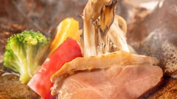 A plate with sliced ham, a piece of broccoli, and a slice of tomato.