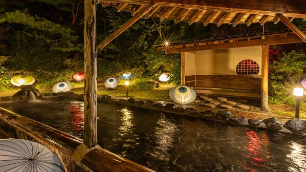 A traditional Japanese garden with a wooden bridge, stone lanterns, and illuminated umbrellas. - KAMENOI HOTEL AKITA YUZE (Kazuno)