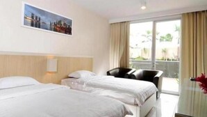 A hotel room with two beds, a chair, a desk, and a large window with curtains. - Hotel Royal Jember (Jember)