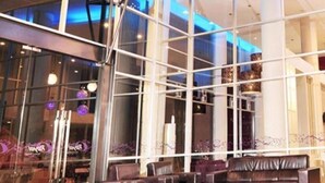 A modern interior with a glass facade, seating area, and a staircase. - Hotel Royal Jember (Jember)