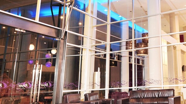 A modern interior with large windows, a leather sofa, and a glass partition. - Hotel Royal Jember (Jember)