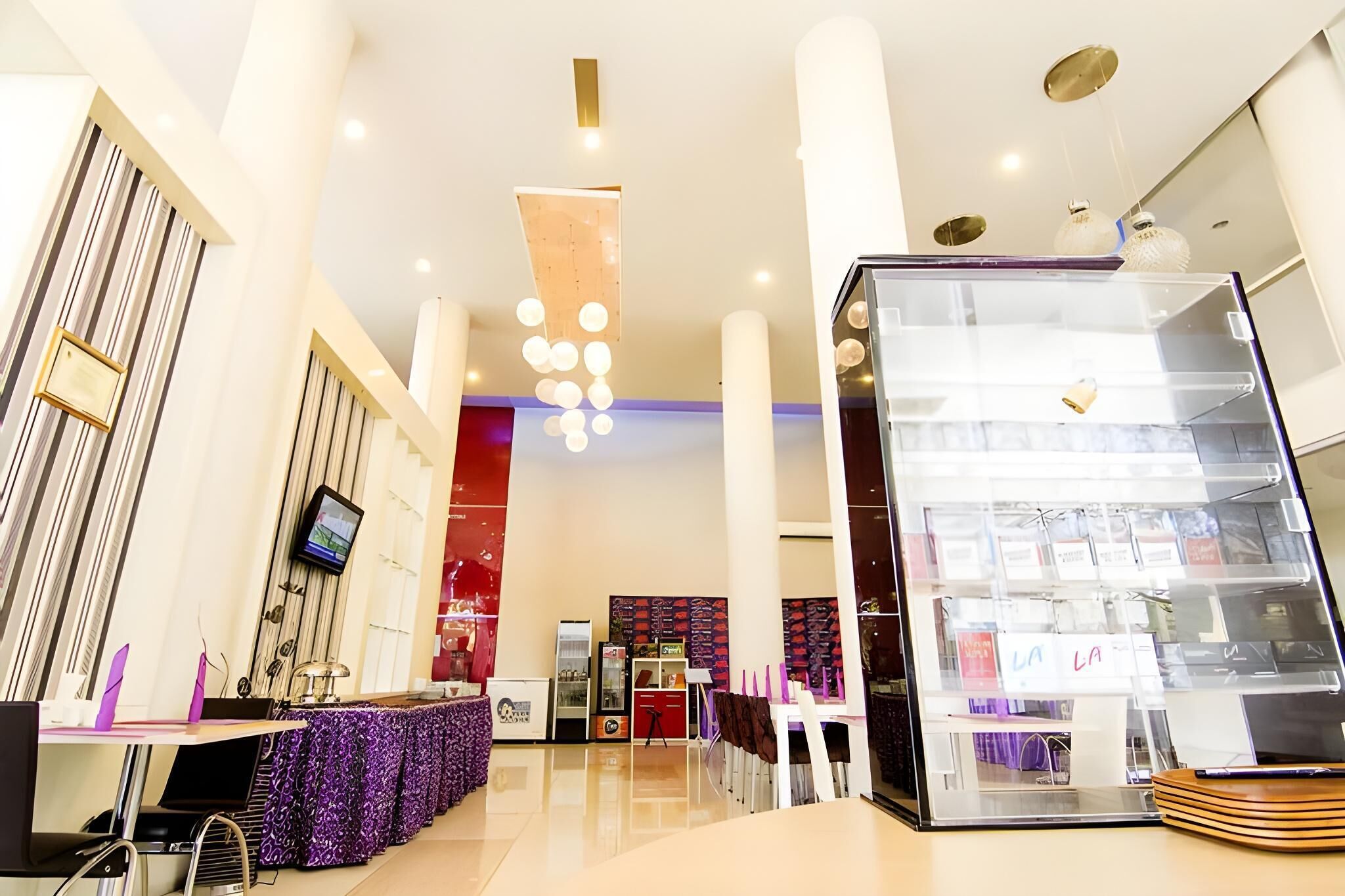 A modern interior with a reception desk, a large display case, and a seating area with purple chairs.