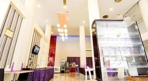 A hotel lobby with a reception desk, a large chandelier, and a display case with items.