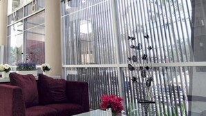 A room with a large window, a sofa, and a vase with flowers. - Hotel Royal Jember (Jember)