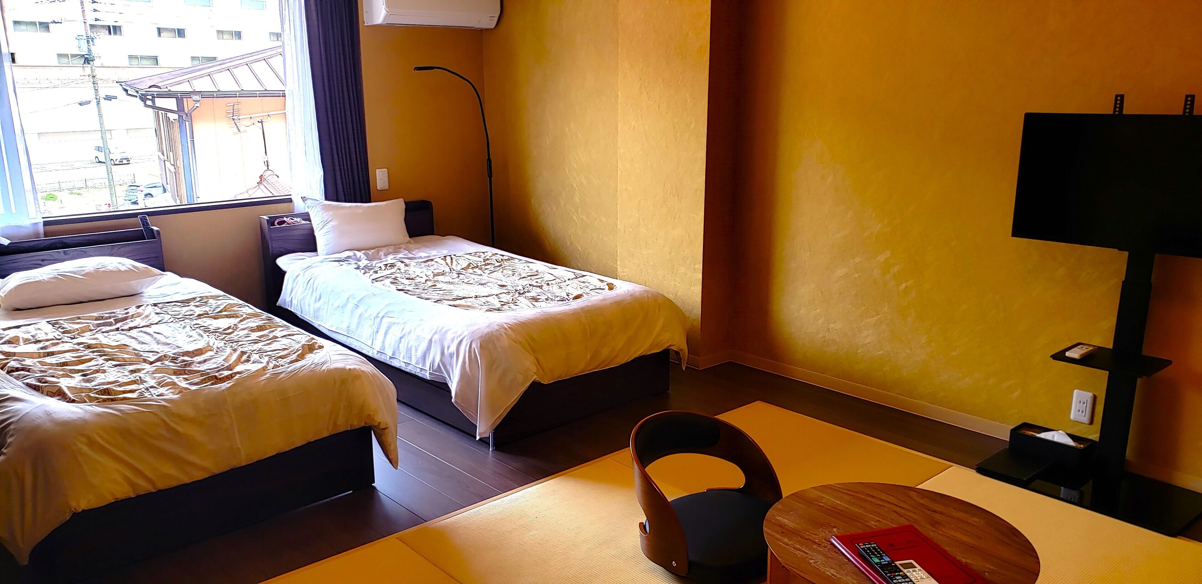 Une chambre d’hôtel avec deux lits, un bureau, une chaise, une lampe et un téléviseur.