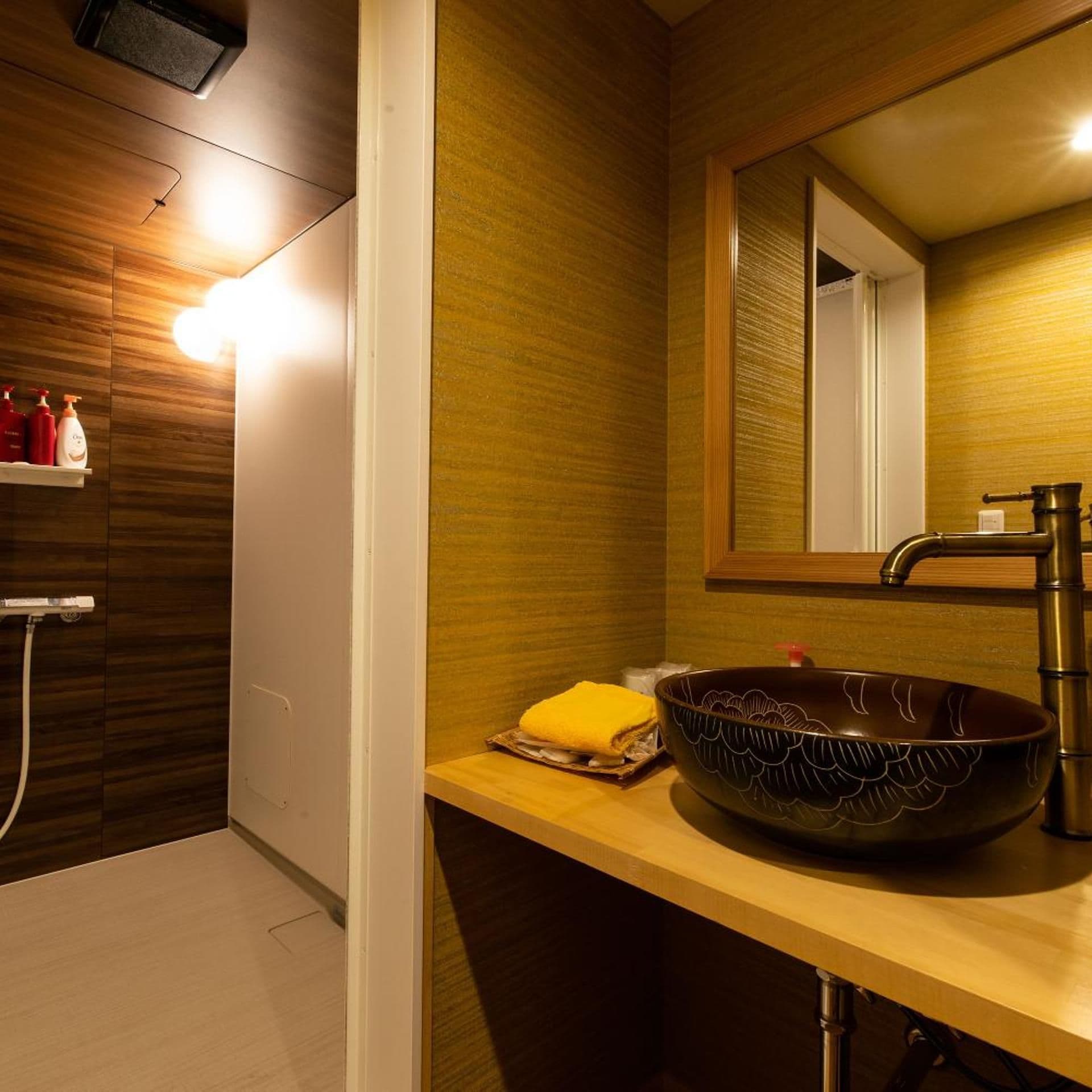 A modern bathroom with a wooden vanity, a large mirror, a vessel sink, and a shower area.