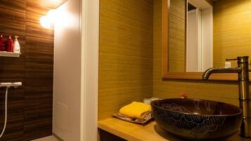 A modern bathroom with a wooden vanity, a large mirror, a vessel sink, and a shower area.