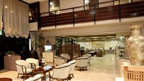 A spacious lobby with a high ceiling, multiple seating areas, and a large decorative vase. - Unzen Sky (UNZEN)