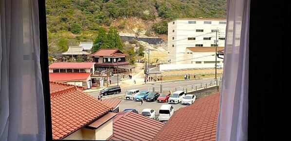 A view of a parking lot with several cars, a bus, and buildings in the background. - Unzen Sky (UNZEN)