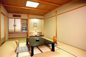 A traditional Japanese room with tatami flooring, a low table, a chair, and a television. - Unzen Sky (UNZEN)