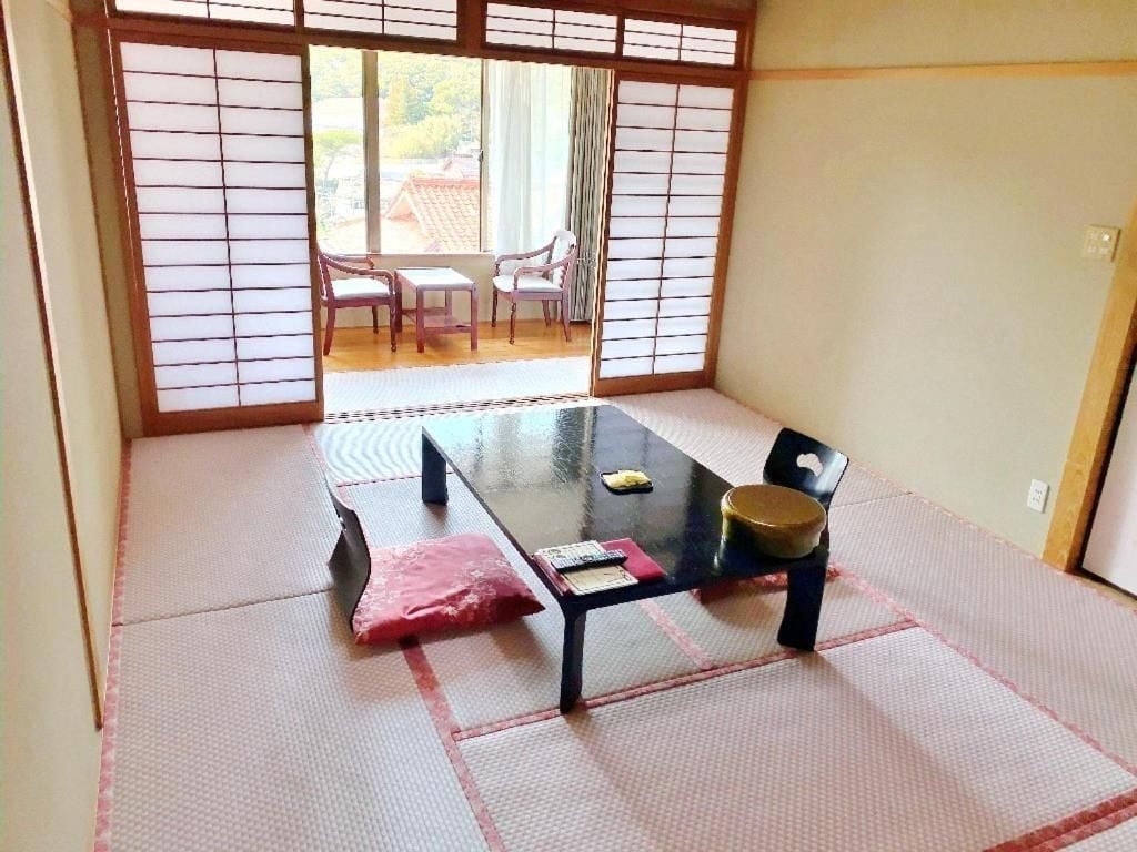 A tatami mat room with a low table, chairs, and sliding doors.