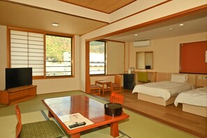 A hotel room with a bed, a desk, a television, and a view of the outdoors. - Unzen Sky (UNZEN)