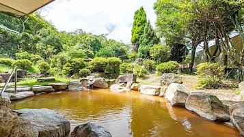 A tranquil garden with a pond, surrounded by rocks and lush greenery.