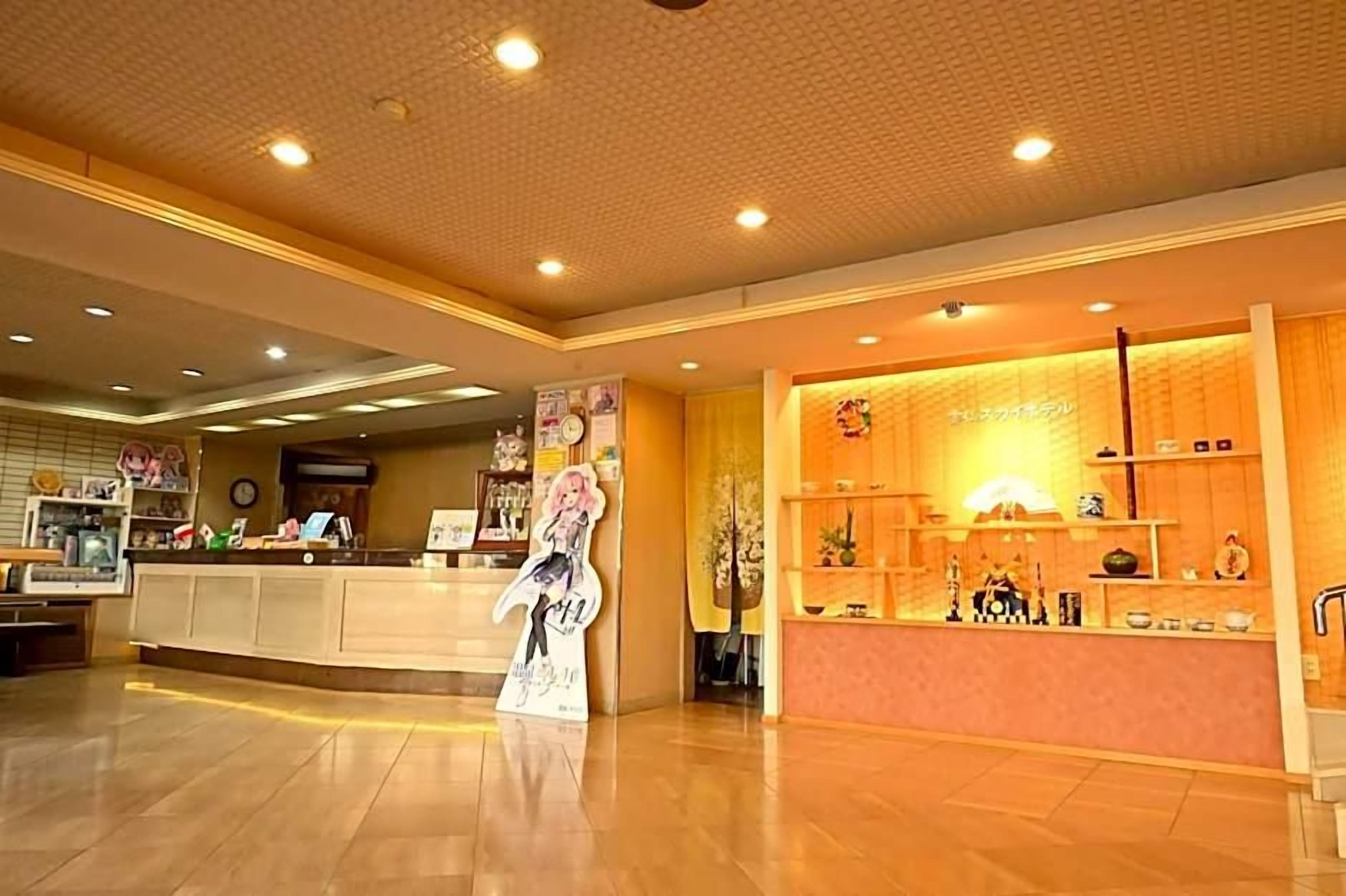 A hotel lobby with a reception desk, a poster, and a display counter with various items.