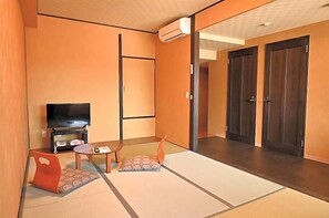 A room with tatami flooring, a television, a small table, and a sofa. - Unzen Sky (UNZEN)