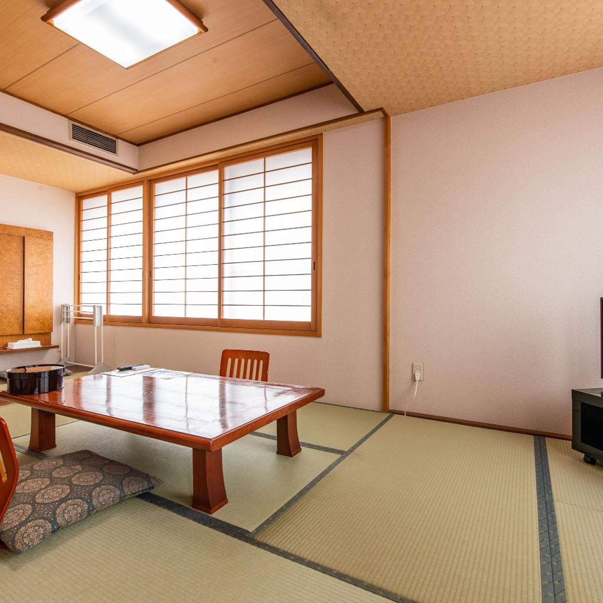 A traditional Japanese room with tatami flooring, a low table, and sliding doors.