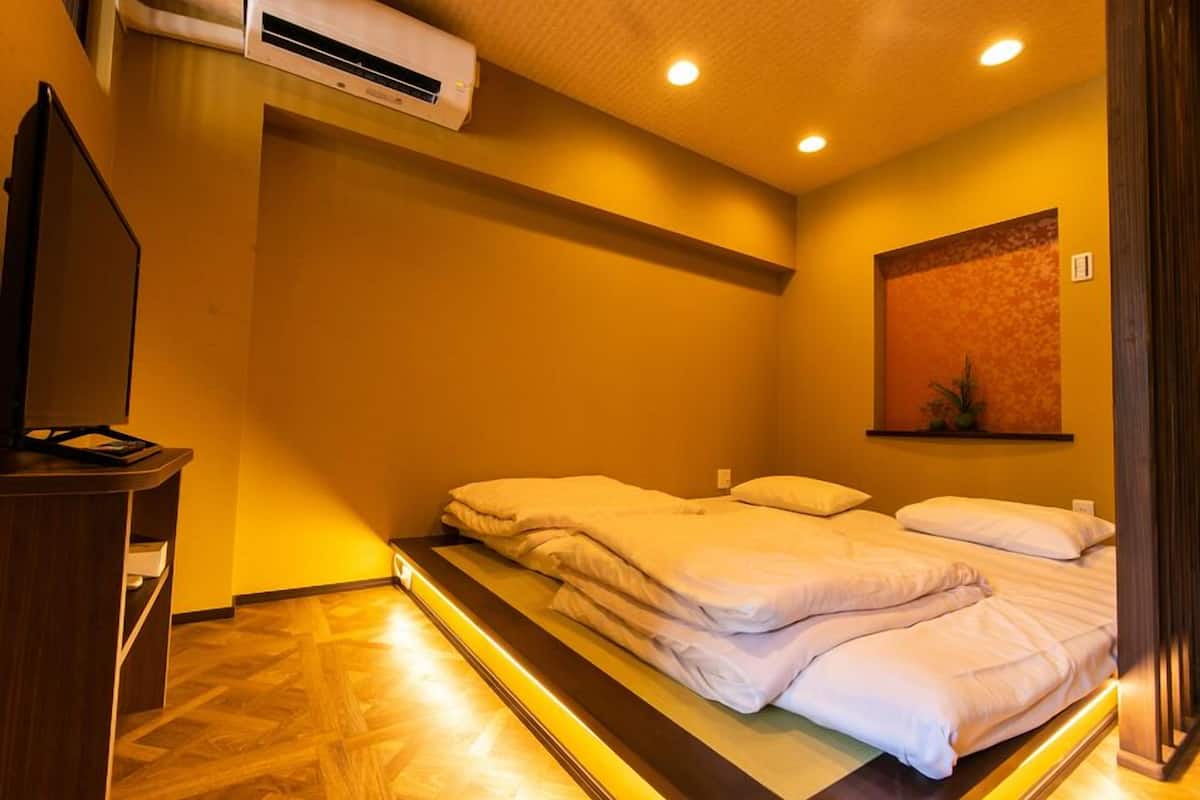 A hotel room with a bed, a desk, and an air conditioning unit.